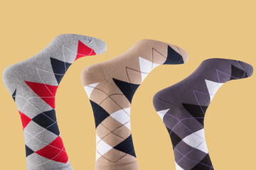 three inverted legs in socks with a pattern of colored rhombuses, on a yellow background