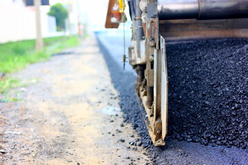close up part of asphalt paver machine with asphalt stream