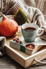 Autumn morning coffee. A cup of coffee on a wooden tray and a warm sweater against a background of autumn leaves. Still life concept.