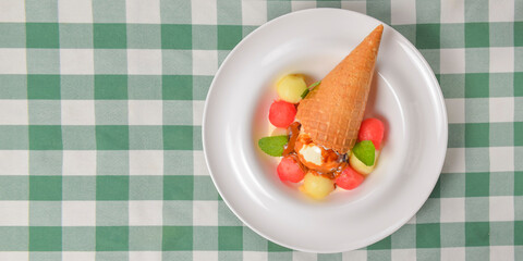 Refreshing melon ice cream with a cone in a white plate. Delicious summer dessert. Cold ice cream fruit sorbet.
