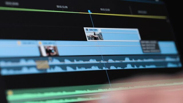 Detail shot of the timeline of a video editing software and the hands of the editor on foreground