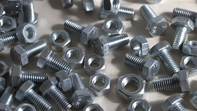 Metal fasteners bolts and nuts fall on the table