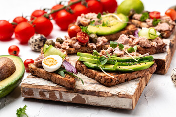 Bruschetta collection with tuna, quail egg, cherry tomatoes, avocado, microgreen and capers, Tasty tuna sandwiches. Food recipe background. Close up