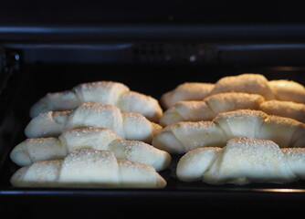 Croissants, sprinkled with sesame and sugar on a baking sheet in the kitchen oven, are ready to be baked.Homemade cake.