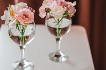 Cut flowers in glasses of water. Mini composition for table decoration.