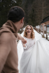 Fototapeta na wymiar groom and bride walking in winter forest park. outdoors snowy day