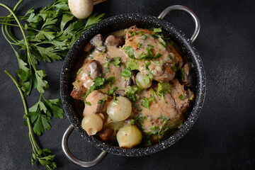 Fricassee - French Cuisine. Chicken stewed in a creamy sauce with mushrooms in casserole pan on a...