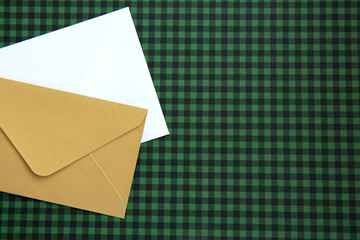 White and beige envelopes and on a green checkered background. Blank template