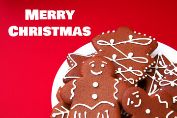 Tasty homemade Christmas gingerbread cookie of various shapes with sugar glaze on a bright red background with copy space. Close up