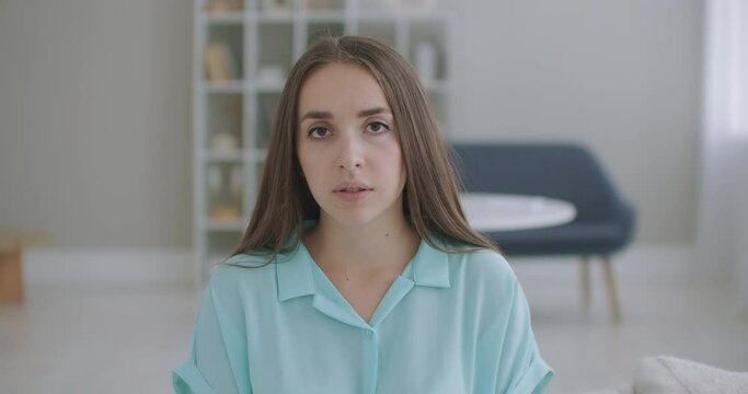 The woman listens while looking at the camera and nods her head approvingly. Participant in the video call dialog. Video conference listener sitting at home