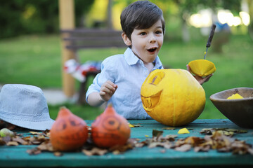 Fototapeta premium Autumn traditions and preparations for the holiday Halloween. A house in nature, a lamp made of pumpkins is cutting out at the table.