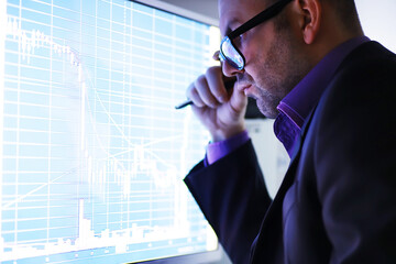 A businessman is looking at a graph on a monitor. An exchange broker evaluates stock market trends....
