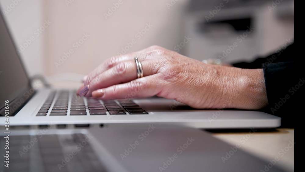 Poster woman hand working on a notebook using touchpad and keyboard, close up. slow motion.
