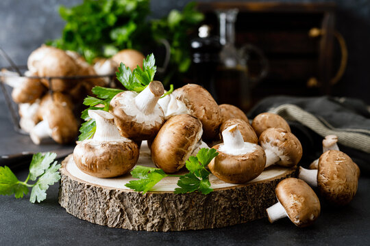 Raw mushrooms champignons on black background, cooking fresh champignons.