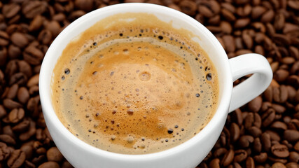 cup of black coffee with froth on coffee beans top view