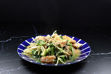 Fried and stirred sliced ginger with sea bass fish and spring onion on the plate. Famous appetizer seafood menu in Asia restaurant. 