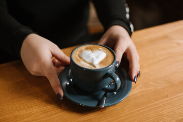 A waiter gives cappuccino with heart on the foam closeup