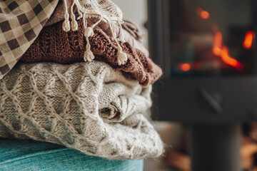 A stack of warm clothes in a wicker basket an iron fireplace