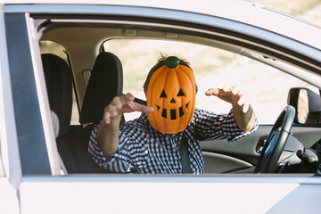 Man inside a car with a pumpkin mask of jack o lantern Hallowwen scaring