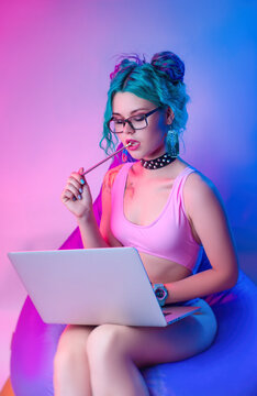 A Woman In A Bright Bathing Suit With Blue Hair Is Sitting On A Chair Bag With A Laptop