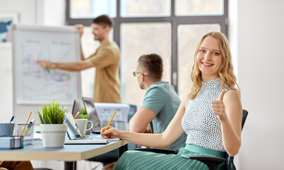 business, work and people concept - smiling businesswoman showing thumbs up at office conference