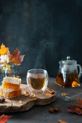 Cozy autumn concept, hygge. Cup of hot black tea with steam, honey combs, autumn leaves on wooden tray. Strengthening immunity. Side view, copy space. Autumn tea party