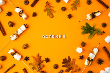 OCTOBER text . Cinnamon marshmallows leaves and anise on yellow background. Fall composition....