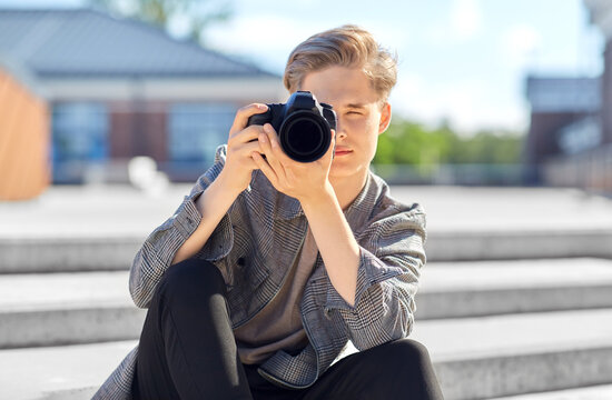 leisure, technology and people concept - young man or teenage boy with digital camera photographing in city