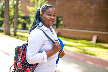 Beautiful smiling young african woman wearing white t-shirt and holding a copybook