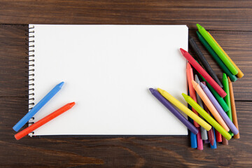 colored crayons and blank page on the wooden table