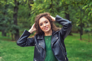 Portrait of a young happy girl in a leather jacket on a walk in the autumn Park