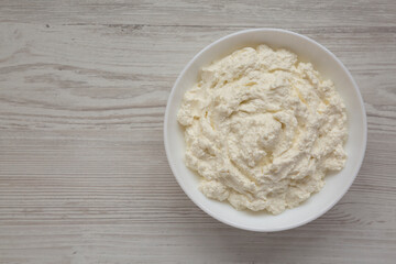 Tasty Ricotta Cheese in a white bowl, top view. Overhead, from above, flat lay. Copy space.