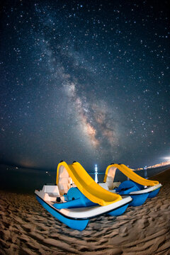 Colorful pedalos on the beach under the milky way galaxy