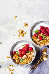 Muesli with raspberries and yoghurt in gray bowl, top view, copy space, Healthy food concept.