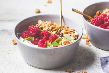 Muesli with raspberries and yoghurt in gray bowl. Healthy food concept.