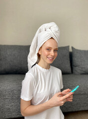 Young smiling woman with a towel on her head sitting at home on the floor looks at the camera.