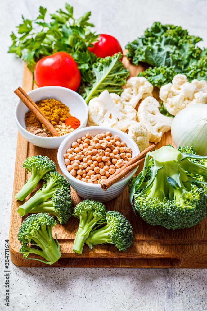 Canvas Prints Cooking background of fresh vegetables, spices and beans. Raw ingredients for cooking vegetarian curry with vegetables and chickpeas on a wooden board.