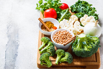 Cooking background of fresh vegetables, spices and beans. Raw ingredients for cooking vegetarian curry with vegetables and chickpeas on a wooden board.