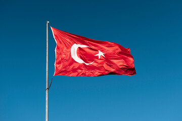 Turkish national flag waving in blue sky.