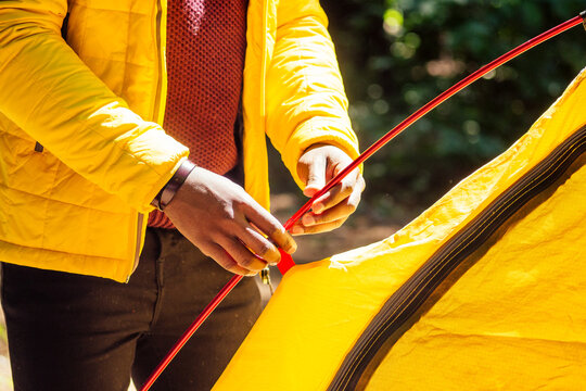 african american in yellow jacker putting on a tent in forest