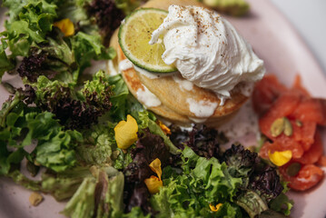 Fototapeta na wymiar A green salad with poached egg, pancakes and salmon