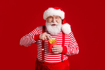 Portrait of his he nice handsome cheerful cheery hungry bearded Santa father eating fried delicious potato delivery lunch snack newyear isolated bright vivid shine vibrant red color background