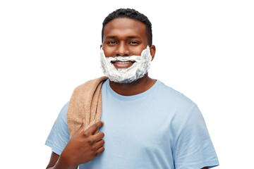 grooming and people concept - smiling african american young man with shaving cream on his beard and bath towel over white background