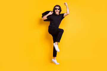 Fototapeta na wymiar Full length photo of young man hold shopping packs open mouth raise hand wear black t-shirt pants white sneakers specs isolated yellow color background