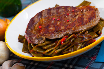 Delicious fried beef loin served with vegetable garnish of stewed green beans and red bell pepper