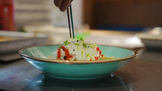 Apprentice cook chef kitchen practicing beautiful presentation dishes visitors cafe. Tweezers add herbs to the salad in detail. Cooking as an art. The aesthetic design of the dish in the restaurant.