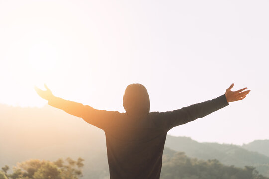 Copy space of man rise hand up on top of mountain and sunset sky abstract background.