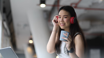 Female teenager listening music with headphone and relaxing with coffee