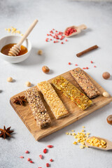 Healthy snacks, fitness lifestyle and high fiber diet concept with granola energy bars surrounded by dried fruits, and hazelnuts on a white stone. Side view