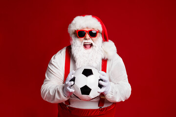 Portrait of his he attractive cheerful cheery ecstatic fat white-haired Santa holding in hands soccer ball having fun isolated bright vivid shine vibrant red burgundy maroon color background